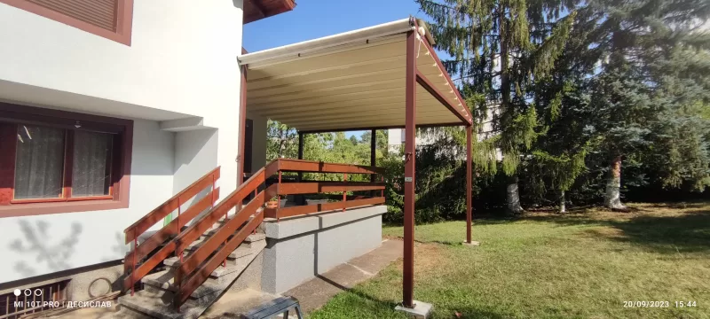 Пергола с цветя и зеленина за уютно градинско пространство.